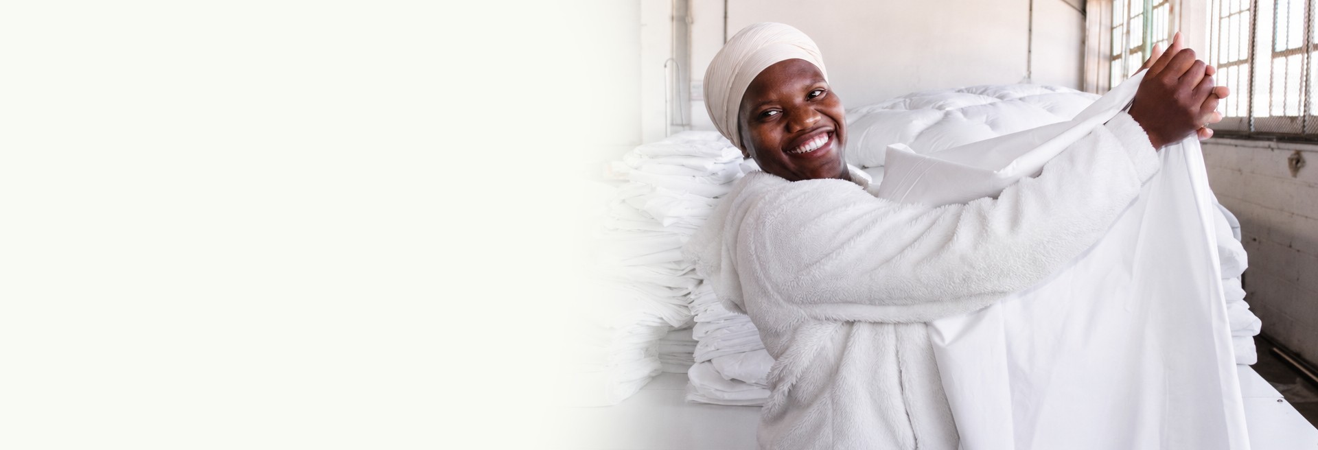 A woman smiling while holding a white duvet